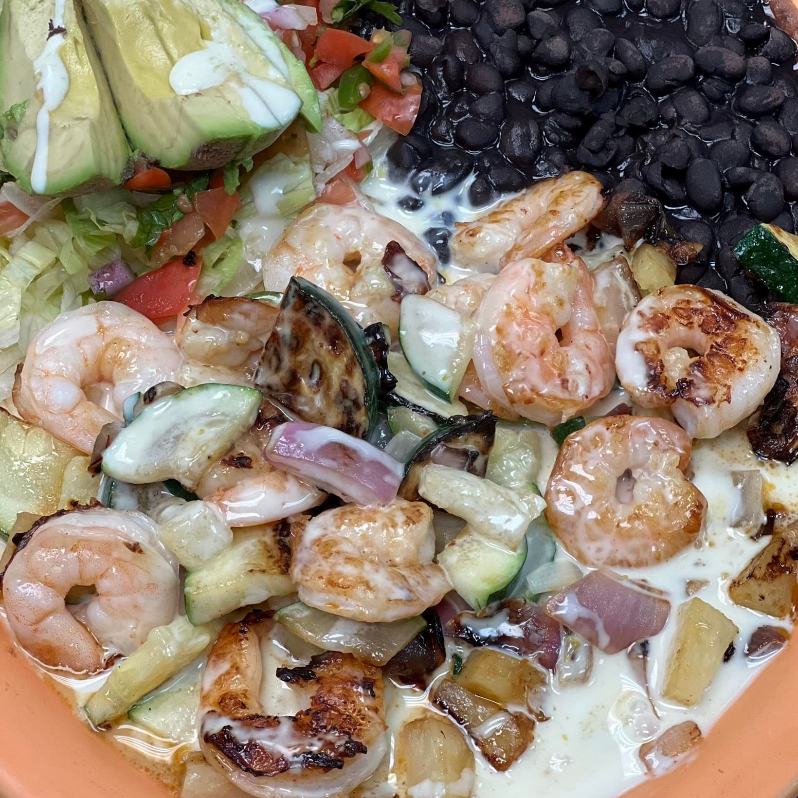 Shrimp, zucchini and onions covers in a cheese sauce with black beans and avacado