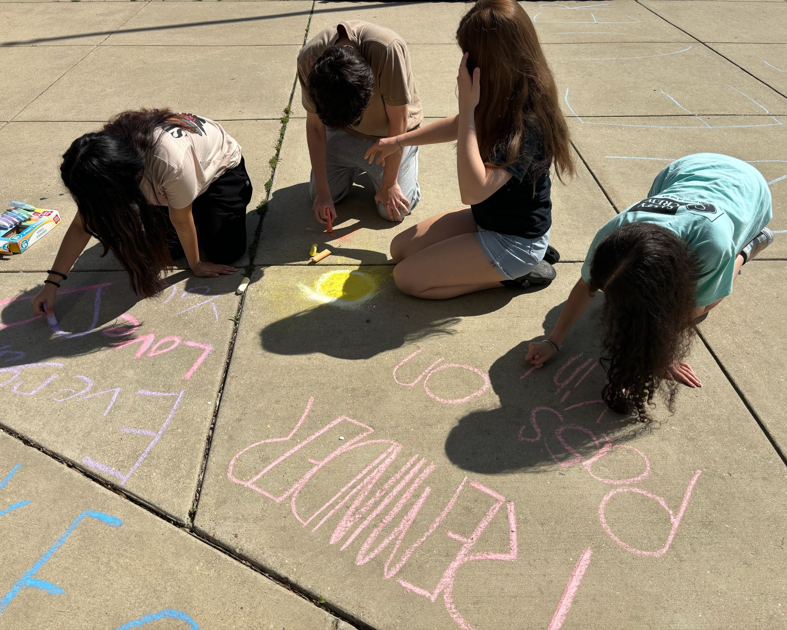7 students drawing with chalk in front of Calvert High School.